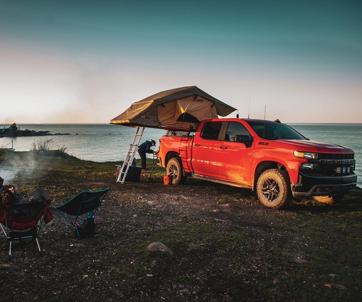 Rooftop tent set up on XBRS bed bars on a Chevy Silverado at a lakeside camp