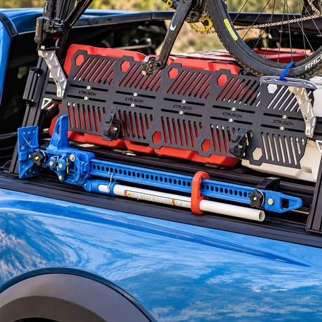 XTR1 with hi lift jack mounted to the extrusion holding a jack to the side of blue truck