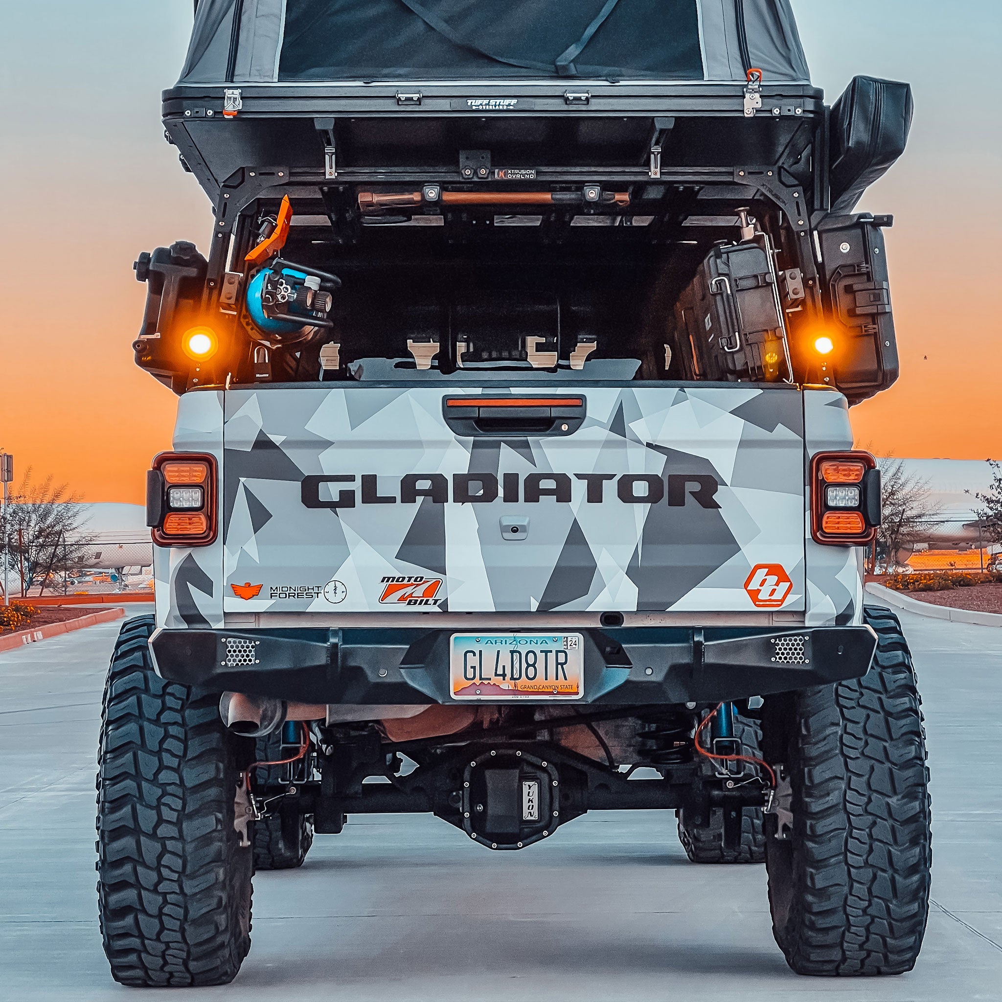 Image of back side of built Jeep Gladiator with 9 Degree XTR3 - 22 inch high bed rack, open roof top tent, awning, storage cases, shovel, Power Tank, and off-road gear.