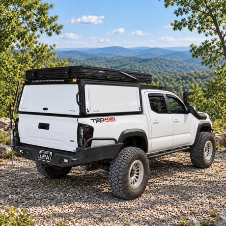 Toyota Tacoma with rooftop tent mounted on white XOSKLTN truck cap 