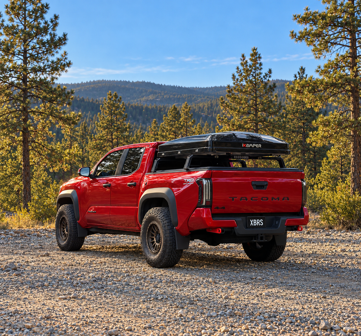 Hard-shell rooftop tent on XBRS bed bars on a red 2024+ Toyota Tacoma TRD Off-Road in a pine forest