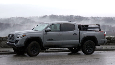 Gray 2016-2023 Toyota Tacoma TRD with an XTR3 bed rack over a Retrax XR cover, side view at a foggy overlook