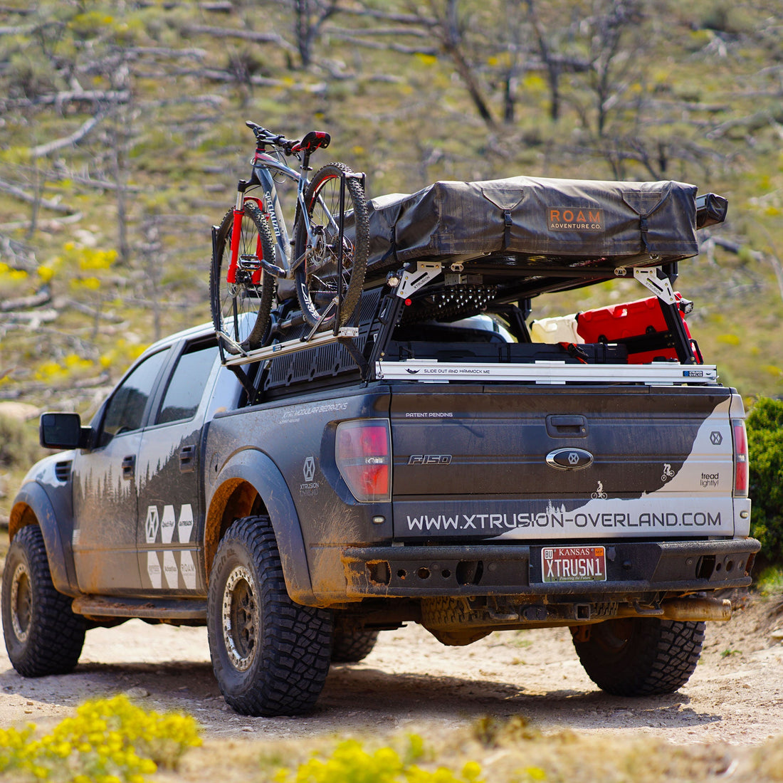 Gen 1 Ford Raptor Xtrusion Overland Bed Rack with Rotopax’s mounted, Molle panels, Mountain Bike, awning, and Roof top tent.