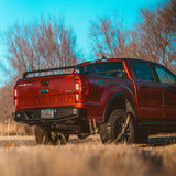 XBRS bed bars on a red Ford Ranger, low rear three-quarter view in a dry field